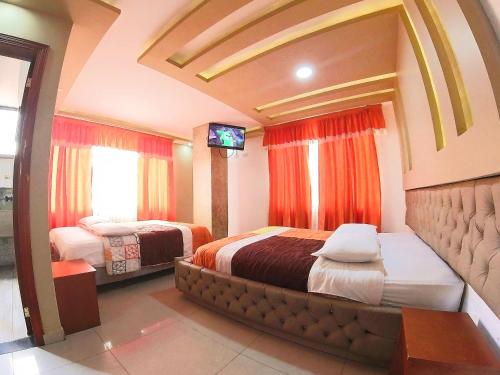 a bedroom with two beds and a flat screen tv at Hostal Dugan in Baños