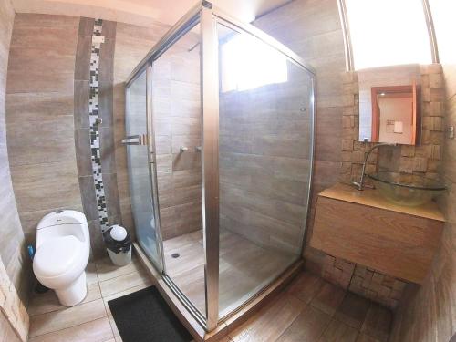 a bathroom with a shower with a toilet and a sink at Hostal Dugan in Baños