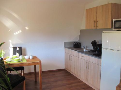 a kitchen with a table and a white refrigerator at Ferienwohnung Orchidee am Neckar in Villingen-Schwenningen