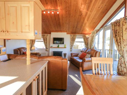 a living room with leather couches and a kitchen at Kellet Lodge Lakeside 26 in Carnforth
