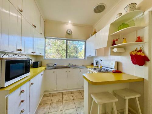 a kitchen with white cabinets and a microwave at Raspberry Terrace of Leura in Leura
