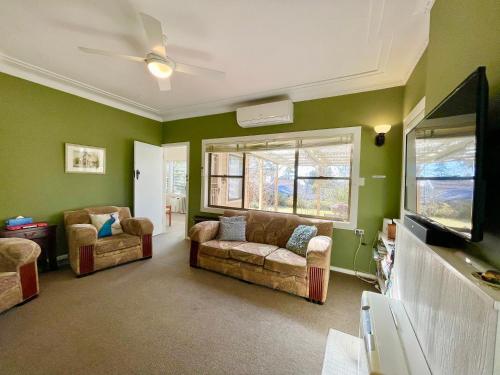 a living room with two couches and a tv at Raspberry Terrace of Leura in Leura