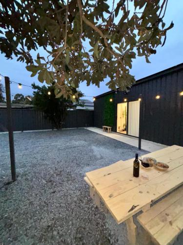a bottle of wine sitting on a picnic table in a backyard at 24C - Modern 2BR Apartment in Gawler in Gawler