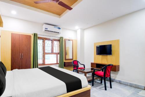 a bedroom with a bed and a desk and a tv at Super Hotel O Gurudwara Near RTC Complex in Visakhapatnam