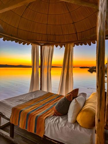 a bed under a umbrella with a view of the water at Amalia Titicaca Lodge in Puno
