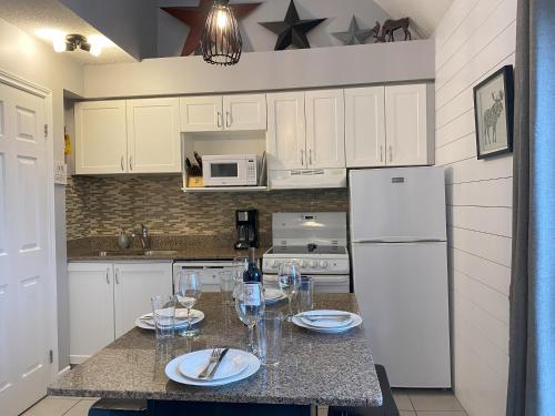 a kitchen with a table with plates and wine glasses at Blue Mountain 2 Story Studio Loft in Blue Mountains