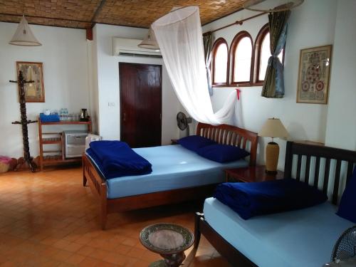 a bedroom with two beds and a table and windows at Mut Mee Garden Guest House in Nong Khai