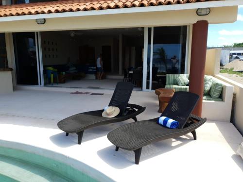 two chairs sitting on a patio next to a swimming pool at Cactus Beachfront villa in Zihuatanejo- pets welcome! in Zihuatanejo