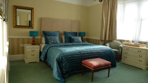 a bedroom with a bed with a blue blanket and a chair at Beech House Hotel in Reading