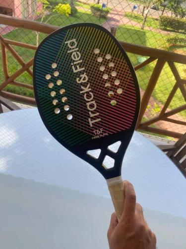 a person holding a tennis racket in front of a table at Praia da Espera - Paraíso em Itacimirim - Quinta das Lagoas Reserva in Monte Gordo