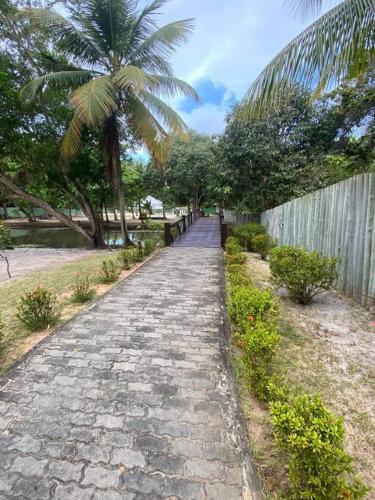 a cobblestone path next to a fence and a palm tree at Praia da Espera - Paraíso em Itacimirim - Quinta das Lagoas Reserva in Monte Gordo