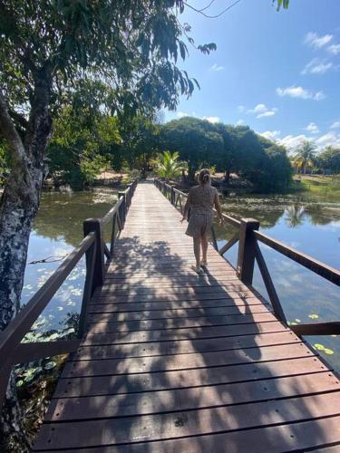 a woman walking on a bridge over a body of water at Praia da Espera - Paraíso em Itacimirim - Quinta das Lagoas Reserva in Monte Gordo