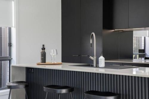 a kitchen with a sink and two bar stools at Eve House 2 Thurgoona in Thurgoona