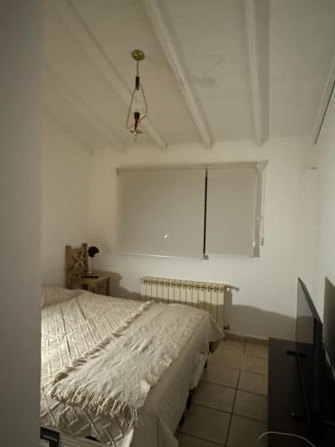 a white bedroom with a bed and a window at Mirando al canal in Ushuaia
