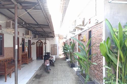 a motorcycle parked next to a building with plants at Tutus Homestay Syariah RedPartner in Bugul
