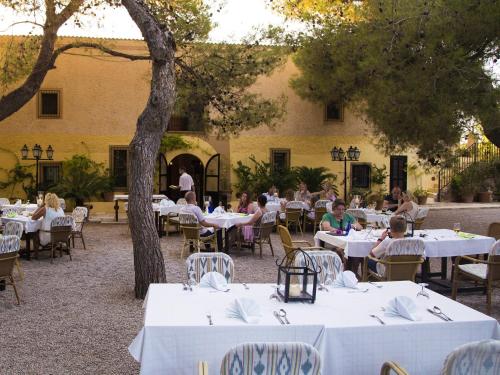 a group of people sitting at tables in front of a building at Finca Hotel Rural Predio Son Serra in Can Picafort