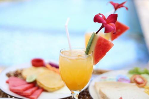 a glass of orange juice next to a plate of food at NG Sweet Home in Nusa Penida