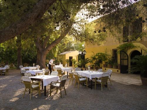 a restaurant with white tables and chairs under trees at Finca Hotel Rural Predio Son Serra in Can Picafort