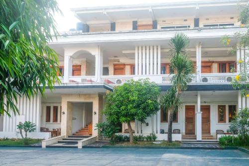 a large white building with palm trees in front of it at Urbanview Omah Pari Boutique Hotel in Yogyakarta