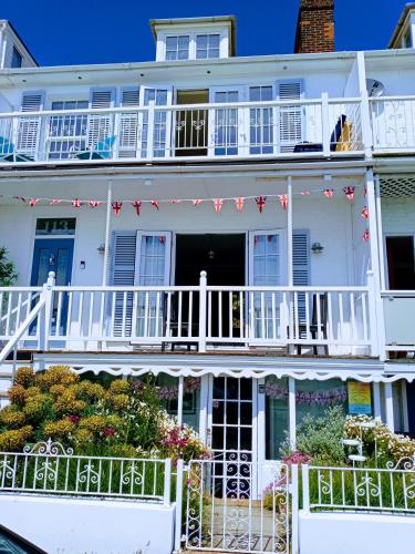 a white house with a balcony with red and white flags at Beachfront Studio Apartment in Felixstowe