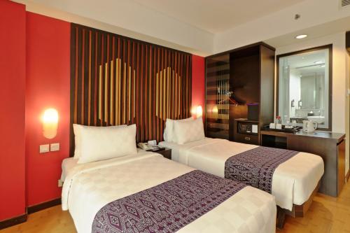 two beds in a hotel room with red walls at Mercure Pontianak City Center in Pontianak