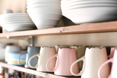 a shelf with plates and mugs on it at J-Hoppers Lake Biwa Guesthouse in Otsu