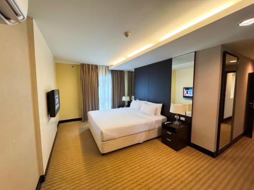 a hotel room with a bed and a mirror at The Narathiwas Hotel & Residence Sathorn Bangkok in Bangkok
