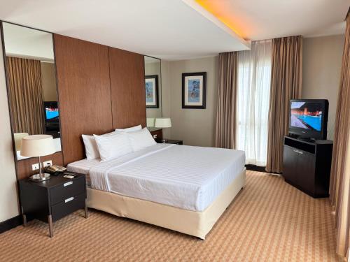 a hotel room with a bed and a flat screen tv at The Narathiwas Hotel & Residence Sathorn Bangkok in Bangkok