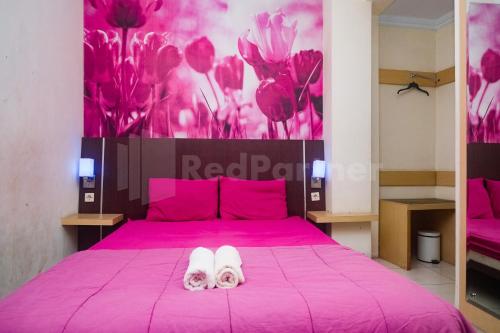 un paio di infradito su un letto rosa di Bies Malioboro Hotel RedPartner a Yogyakarta