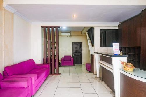 un soggiorno con divano rosa e sedie viola di Bies Malioboro Hotel RedPartner a Yogyakarta
