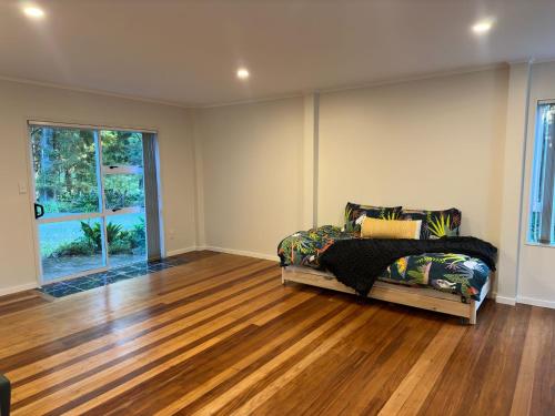 a bedroom with a bed and a wooden floor at The Nature Hub in Parua Bay