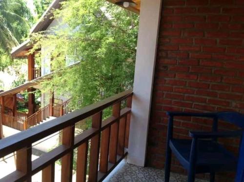 a balcony with a blue chair and a brick wall at Zen NamKhan Riverside in Luang Prabang