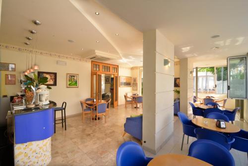 a restaurant with blue chairs and a bar at Hotel Ave in Rimini