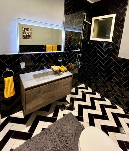 a black and white bathroom with a sink and a mirror at Brightful and joyful 4 bedroom villa in Dubai
