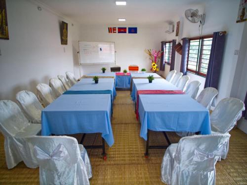 森莫诺隆Manel Guesthouse and Restaurant的有蓝色桌子和白色椅子的会议室