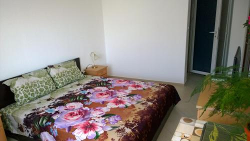 a bedroom with a bed with a floral bedspread at House of Flowers in Ahtopol