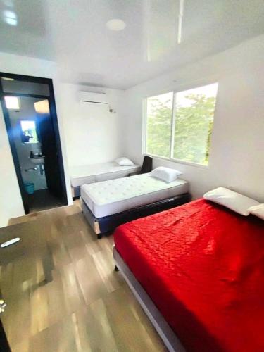 a bedroom with two beds and a red blanket at centro vacacional EL COLIBRI in San Luis de Palenque