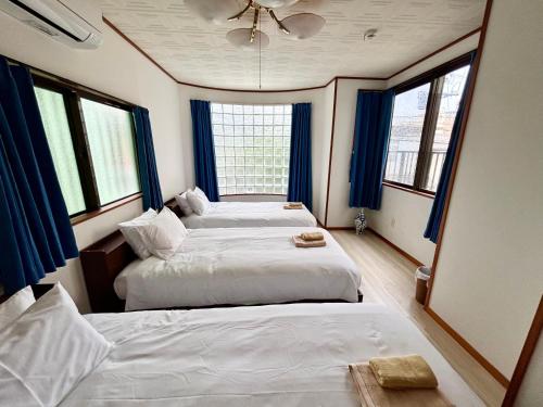 2 camas en una habitación con cortinas y ventanas azules en Umikaji Base WAKASA, en Naha