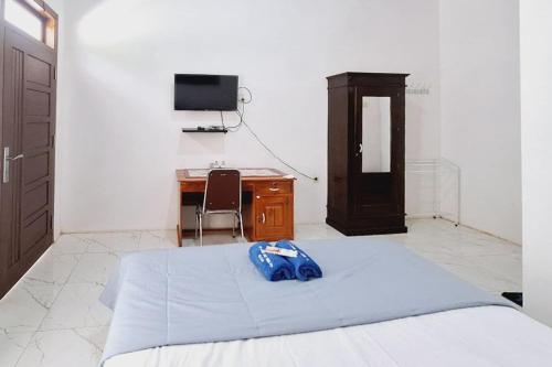 a bedroom with a bed and a desk and a television at Ayani Guest House RedPartner in Blitar
