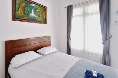 a bedroom with a bed and a painting on the wall at Ayani Guest House RedPartner in Blitar