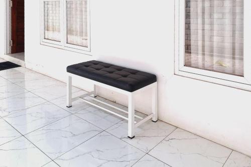 a black bench sitting in a room next to windows at Ayani Guest House RedPartner in Blitar
