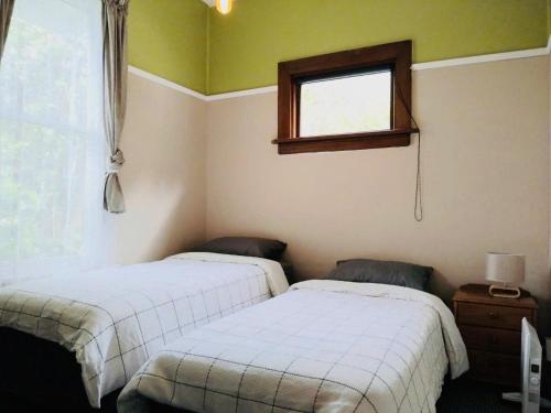 two beds in a room with a window at In Dunedin's Heart, Full House, Full Sun, Full Chill, Why Stay at a Hotel When You Can Afford an Entire House in Dunedin