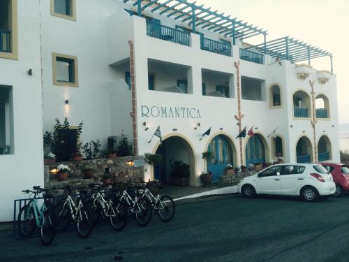 a white car parked in front of a building with bikes at Romantica Hotel in Agia Pelagia Kythira