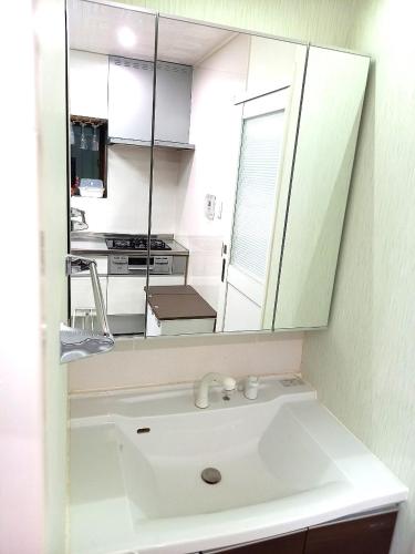 a bathroom with a sink and a mirror at Umikaji Base WAKASA in Naha