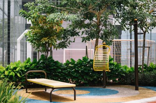 a bench and a yellow chair in a garden at Urban Suites Infinity Pool 3BR 2Carparks 8pax in Jelutong