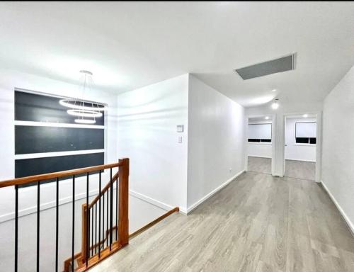 an empty living room with white walls and a staircase at Luxury 5 Bedrooms 3 full Bathrooms home in centre of Rouse Hill in Riverstone