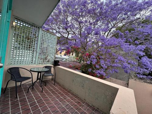 a balcony with two chairs and a table and purple flowers at Lil Darling in Sydney