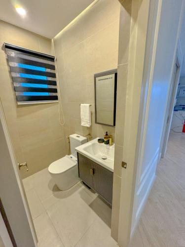 a bathroom with a toilet and a sink and a mirror at The Suite- Luxurious City Skyline in Cebu City