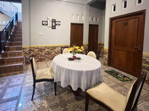 a white table with chairs and a vase of flowers on it at Joglo Dhepis Syariah Borobudur Magelang RedPartner in Magelang