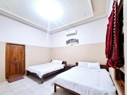 a bedroom with two beds and a window at Joglo Dhepis Syariah Borobudur Magelang RedPartner in Magelang